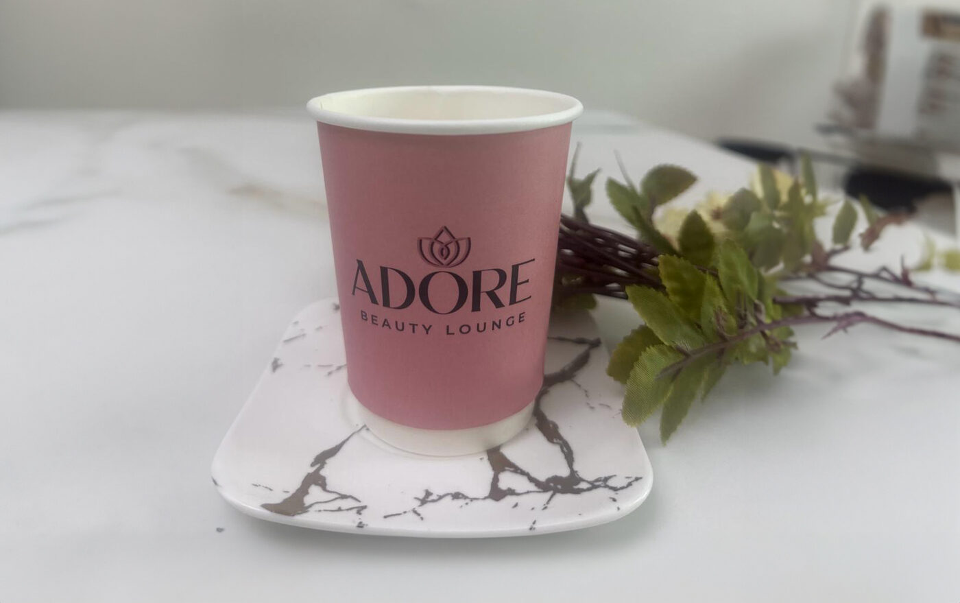 Adore's branded compostable coffee cup with a plant